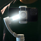 Smartphone mit montiertem Licht und Danxon Gimbal vor dunklem Hintergrund
