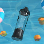 Schwarzer Danxon Tragbarer Mixer vor blauem Unterwasserhintergrund mit Poolspielzeug und Obstscheiben
