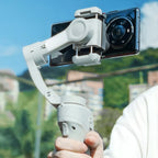 Hand hält einen Danxon Gimbal mit Smartphone vor klarem Himmel und unscharfem Hintergrund
