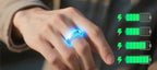 Hand trägt leuchtenden Onevik Smart Ring mit Batteriesymbol-Grafiken vor unscharfem Hintergrund