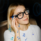 Frau trägt schwarze Meacode AI Smart Glasses mit blauen Musiknoten vor dunklem Hintergrund